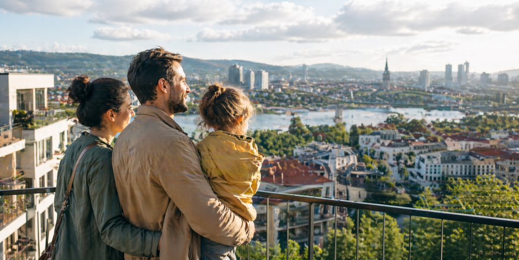 משפחה צעירה עם ילד משקיפה על עיר בסלובקיה ובוחנת מעבר לבית חדש